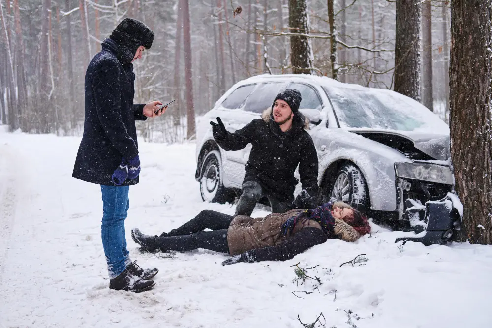 People assisting an injured person after a car accident on a snowy road in Oklahoma City