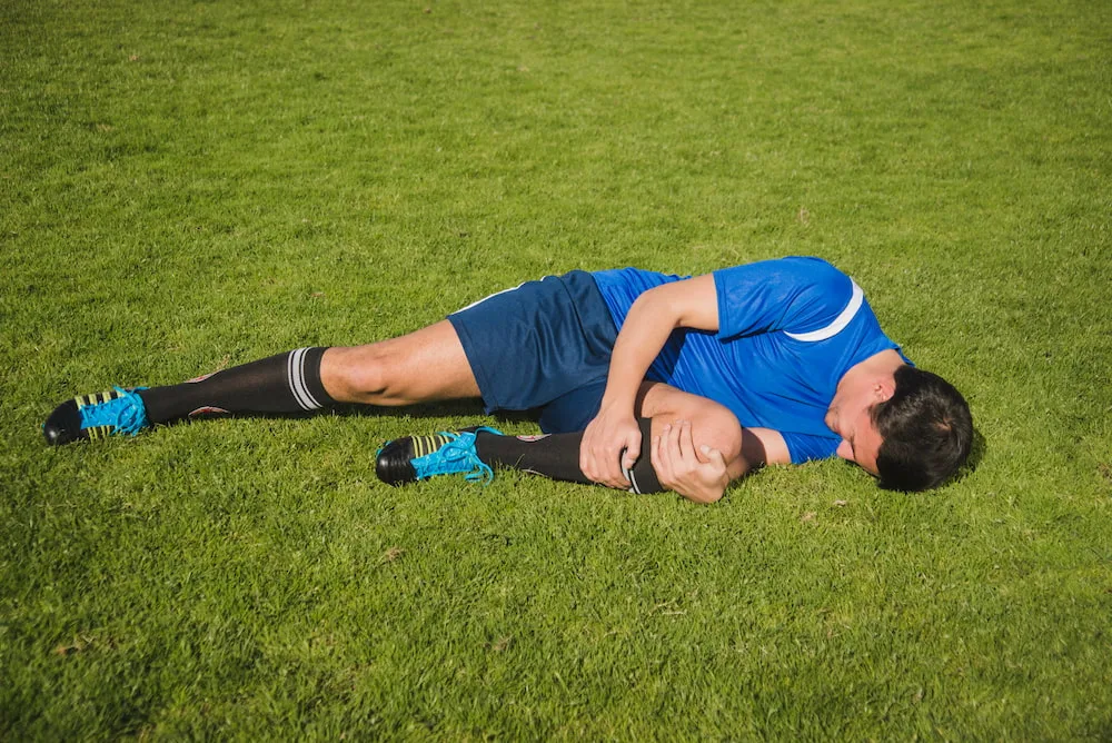 Football player on ground holding knee after injury
