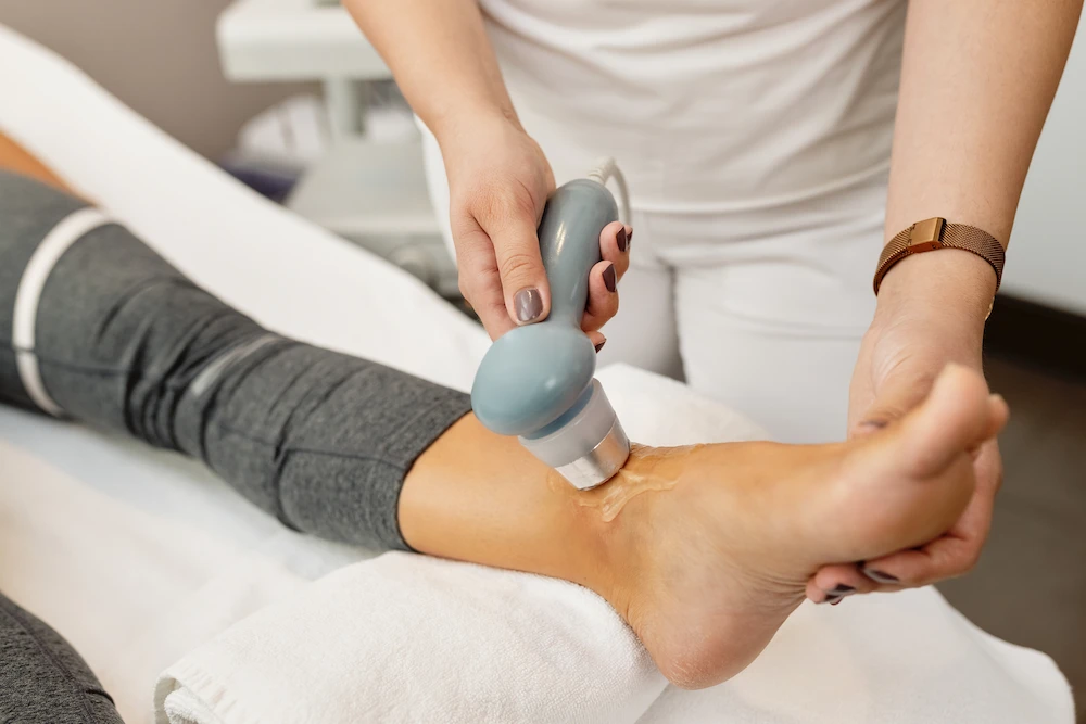 Therapist applying shockwave therapy to ankle for pain relief and recovery support