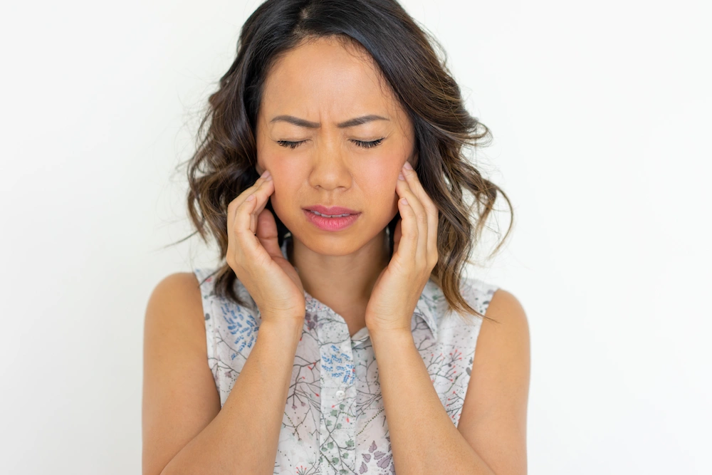 Person experiencing jaw pain caused by TMJ disorder.